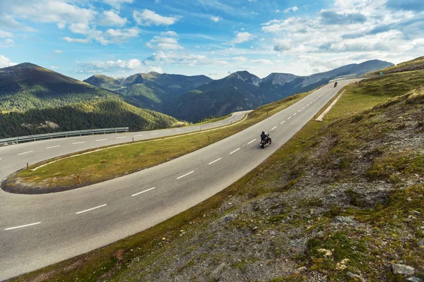 Motociclista a cavallo nel paesaggio alpino. — Foto Stock