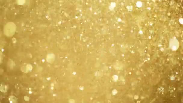 Mouvement super lent de particules dorées scintillantes sur fond noir. Faible profondeur de mise au point. Filmé sur caméra de cinéma à grande vitesse, 1000 images par seconde.