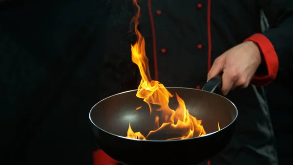 Primo piano di chef che tiene vuoto padella wok con fiamme . — Foto Stock