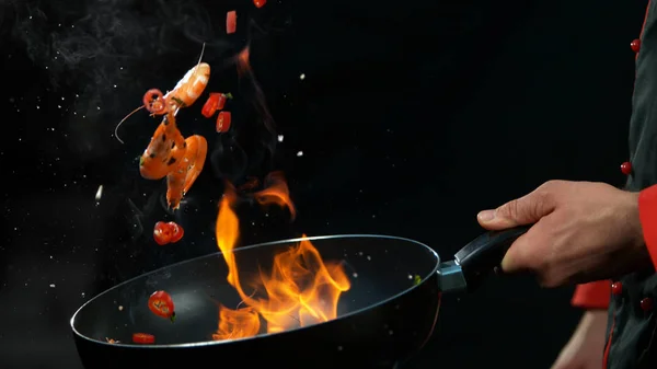 Closeup of chef holding wok pan with falling prawn — Stock Photo, Image