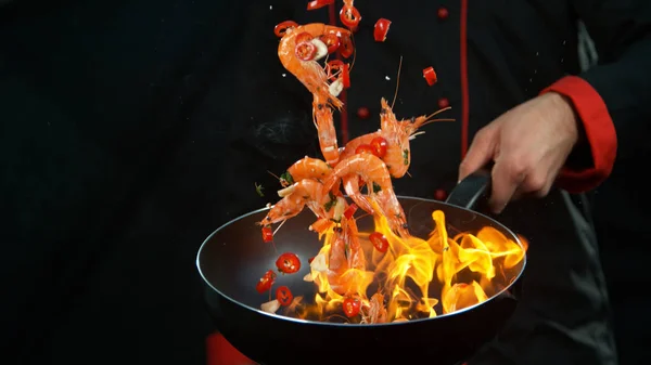 Närbild av kock som håller wok pan med fallande räkor — Stockfoto