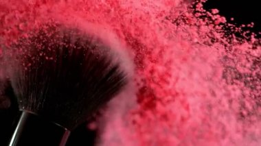 Düşen pembe tozlu, siyah arkaplan makyajlı süper yavaş makyaj fırçası. Yüksek hızlı sinema kamerası, 1000fps.