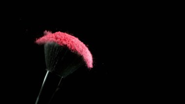 Düşen pembe tozlu, siyah arkaplan makyajlı süper yavaş makyaj fırçası. Yüksek hızlı sinema kamerası, 1000fps.