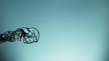 Uçan suyun yumuşak mavi arka planda çok yavaş sıçraması. Yüksek hızlı sinema kamerası, 1000fps.