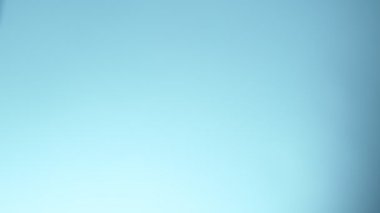 Uçan suyun yumuşak mavi arka planda çok yavaş sıçraması. Yüksek hızlı sinema kamerası, 1000fps.