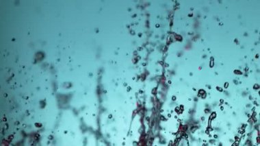 Yumuşak mavi arka planda patlayan suyun süper yavaş akışı. Yüksek hızlı sinema kamerası, 1000fps.