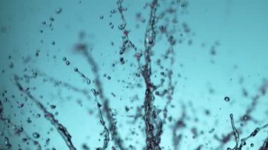 Yumuşak mavi arka planda patlayan suyun süper yavaş akışı. Yüksek hızlı sinema kamerası, 1000fps.