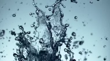 Uçan suyun yumuşak mavi arka planda çok yavaş sıçraması. Yüksek hızlı sinema kamerası, 1000fps.