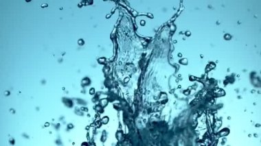 Uçan suyun yumuşak mavi arka planda çok yavaş sıçraması. Yüksek hızlı sinema kamerası, 1000fps.