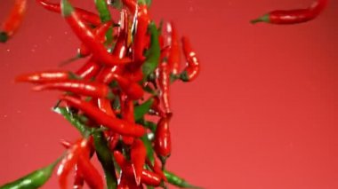 Kırmızı arka planda çarpışan kırmızı biberlerin süper yavaş çekimleri. Yüksek hızlı sinema kamerası, 1000 fps..