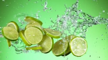 Limon parçalarının su sıçramalarıyla çarpışması, yeşil arka plan. Yüksek hızlı sinema kamerası, 1000 fps..