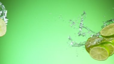 Limon parçalarının su sıçramalarıyla çarpışması, yeşil arka plan. Yüksek hızlı sinema kamerası, 1000 fps..