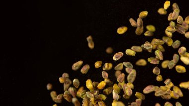 Siyah arka planda uçan fıstıkların gerçekçi dondurucu hareketi.