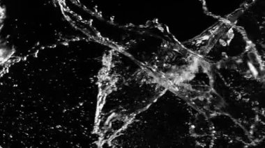 Uçan suyun süper yavaş akımı çarpışma esnasında sıçrar, siyah zemin. Yüksek hızlı sinema kamerası, 1000fps.