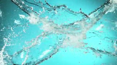 Uçan suyun süper yavaş akımı çarpışma halinde, mavi arka planda. Yüksek hızlı sinema kamerası, 1000fps.