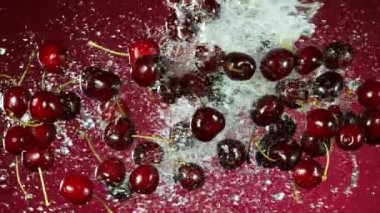 Su sıçramasıyla düşen kirazların süper yavaş çekimi. Yüksek hızlı sinema kamerası, 1000fps