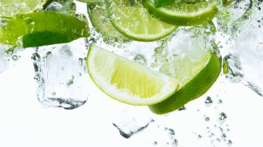 Buz küplü limon dilimleri, beyaz arka planda izole bir şekilde suyun dibine düşüyor.