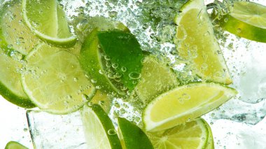 Buz küplü limon dilimleri, beyaz arka planda izole bir şekilde suyun dibine düşüyor.