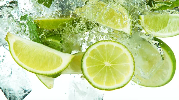 Lime Skivor Med Isbitar Faller Djupt Vatten Isolerad Vit Bakgrund — Stockfoto