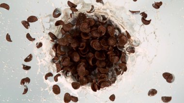 Dönen tahıl parçalarının hareketsiz hareketlerini beyaz arka planda izole edilmiş süt sıçraması ile dondur. Uçan yemek konsepti, sağlıklı yemek..