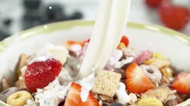 Mısır gevreğiyle dolu kaseye süt dökmenin süper yavaş çekimi, kamera hareketi. Yüksek hızlı sinema kamerası, 1000fps.