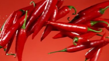 Kırmızı arka planda çarpışan kırmızı biberlerin süper yavaş çekimleri. Yüksek hızlı sinema kamerası, 1000 fps.