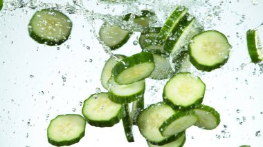 Havada donmuş uçan salatalık hareketi, su sıçraması, beyaz arka planda izole edilmiş.