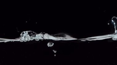 Siyah arka planda izole edilmiş çok yavaş hareket eden su dalgaları. Yüksek hızlı sinema kamerası, 1000 fps..