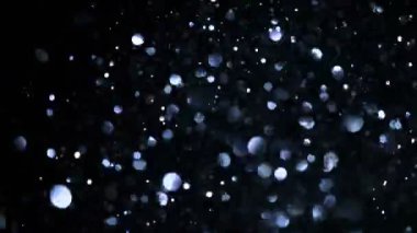 Siyah arkaplanda ışıldayan renkli parçacıkların süper yavaş çekimi. Sığ odak derinliği. Yüksek hızlı sinema kamerası, 1000 fps..