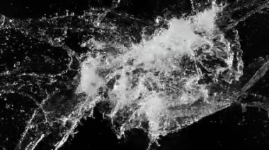 Uçan suyun süper yavaş akımı çarpışma esnasında sıçrar, siyah zemin. Yüksek hızlı sinema kamerası, 1000fps.