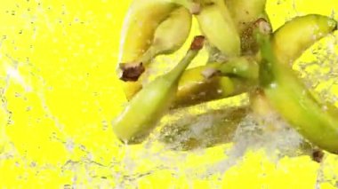 Sarı arka planda muzların havaya vuruşunun süper yavaş çekimi. Yüksek hızlı sinema kamerası, 1000 fps..