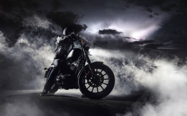 Yüksek güçlü motosikletli helikopterin ayrıntıları ve gece binicisi. Arka planda sis ve dramatik gökyüzü.