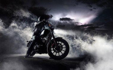 Detail of high power motorcycle chopper with man rider at night. Fog with backlights and dramatic sky on background. clipart