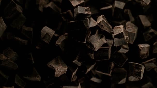 Super Zeitlupe Einer Fliegenden Gruppe Roher Schokoladenstücke Auf Schwarzem Hintergrund — Stockvideo