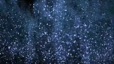 Siyah zemin üzerinde ışıldayan parçacıkların süper yavaş çekimi. Sığ odak derinliği. Yüksek hızlı sinema kamerası, 1000 fps..