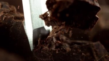 Keskiyle siyah çikolata parçalarını kesmenin süper yavaş çekimi. Sinema, yüksek hızlı kamera, 1000fps.