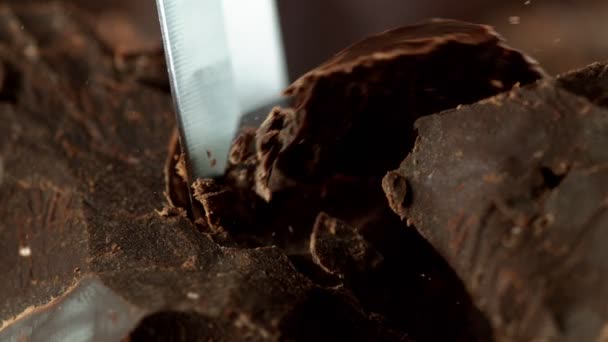 Super pomalý pohyb odřezávání tmavých kousků čokolády dlátem. Natočeno vysokorychlostní kamerou, 1000fps.