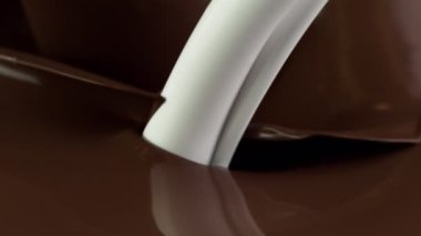 Sıcak çikolata ve sütün çok yavaş bir şekilde dökülmesi. Yüksek hızlı sinema kamerası, 1000fps.