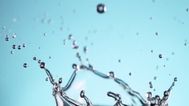 Su sıçratmada süper yavaş çekim, yumuşak mavi arka plan. Yüksek hızlı sinema kamerası, 1000fps.