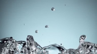 Su sıçratmada süper yavaş çekim, yumuşak mavi arka plan. Yüksek hızlı sinema kamerası, 1000fps.