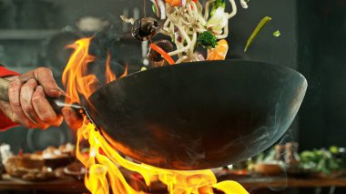 Wok Pan 'ın Dondurucu Hareketi ve Uçan Malzemeler. Arka plandaki Mutfak.