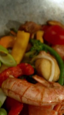 Sebze ve Etli Uçan Asya Yemeklerinin Süper Yavaş Hareketi. Yüksek Hız Sinema Kamerası 'nda çekildi, 600 fps. Kara Arkaplan 'da izole edilmiş, Alevler Yanıp sönüyor. Dikey Görünüm Oranı.