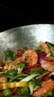 Sebze ve Etli Uçan Asya Yemeklerinin Süper Yavaş Hareketi. Yüksek Hız Sinema Kamerası 'nda çekildi, 600 fps. Kara Arkaplan 'da izole edilmiş, Alevler Yanıp sönüyor. Dikey Görünüm Oranı.