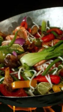 Sebze ve Etli Uçan Asya Yemeklerinin Süper Yavaş Hareketi. Yüksek Hız Sinema Kamerası 'nda çekildi, 600 fps. Kara Arkaplan 'da izole edilmiş, Alevler Yanıp sönüyor. Dikey Görünüm Oranı.