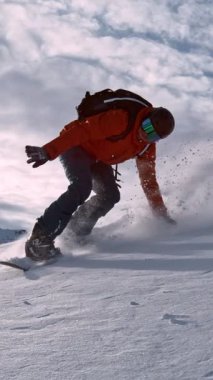 Piste Snowboardcusu 'nun orada. Süper Yavaş Hareket, 1000 fp. Avusturya 'nın Avrupa Alp Dağları' nda açık mavi gökyüzü ile güneşli bir günde Piste yamacında snowboard yapmak. Dikey Görünüm Oranı.