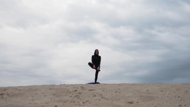 Muslim woman in hijab exercising healthy lifestyle yoga exercise in desert at sunset — Stock Video