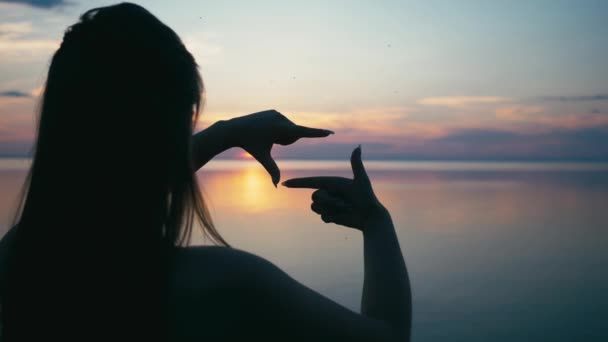 Joven alegre haciendo marco con las manos. Retrato de mujer mirando a través de una cámara imaginaria hecha con los dedos. Señora atractiva durante las vacaciones de verano — Vídeos de Stock