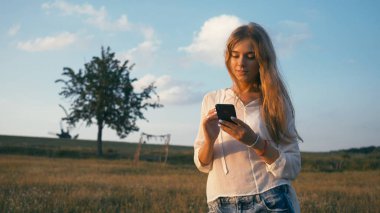 Cep telefonu kullanan kadın yaz parkta. Otantik yaratıcı atış