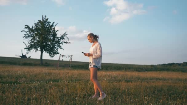 Donna nel parco estivo utilizzando il telefono cellulare. Autentico colpo creativo — Video Stock