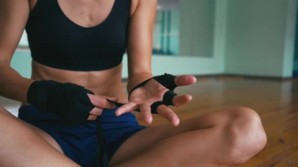 Hermosa mujer de raza mixta Kickboxing poniéndose un vendaje de envolturas de perforación en un estudio de fitness cuerpo en forma de fuerza feroz — Vídeos de Stock